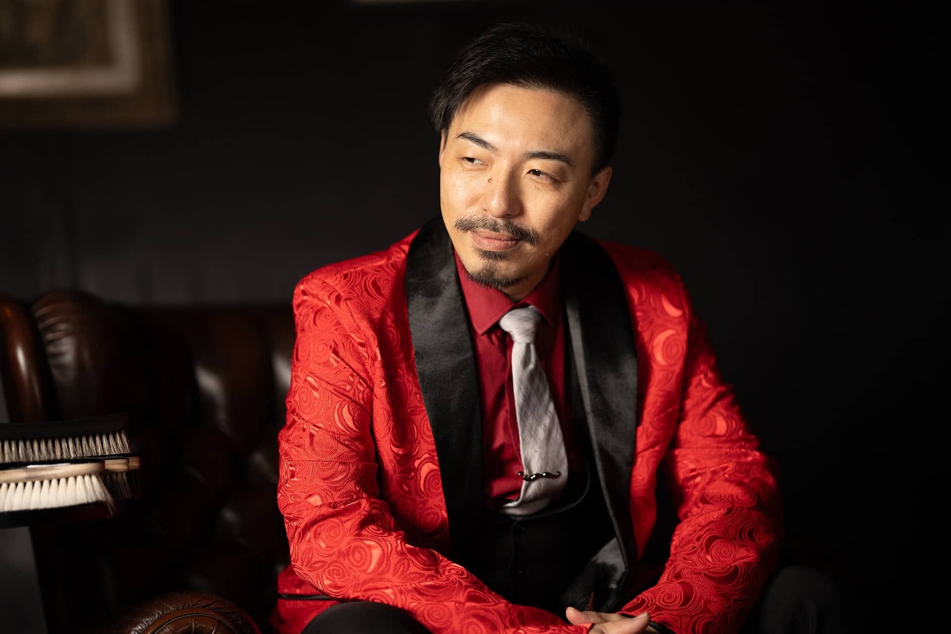 赤いジャケット姿で椅子に座る10分セミナー登壇者の水野嘉彦さん